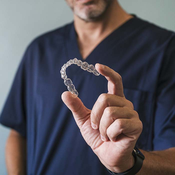 Male orthodontist holding an Invisalign clear aligner